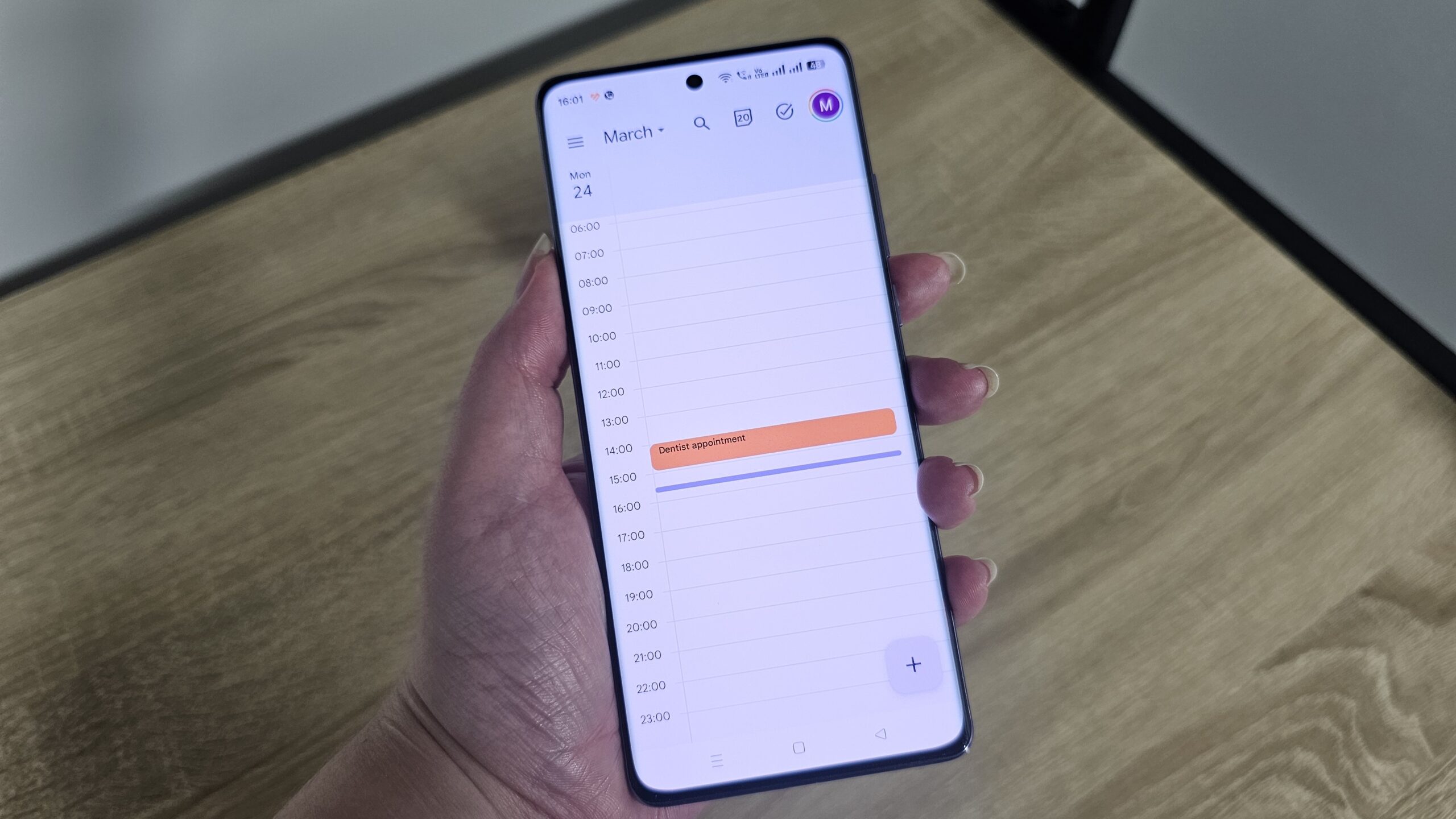 Alguien que sostiene un teléfono inteligente con el calendario de Google en la pantalla Alguien que sostiene un teléfono inteligente con el calendario de Google en la pantalla